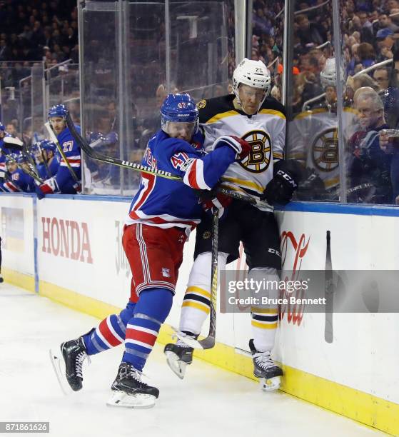 Steven Kampfer of the New York Rangers hits Riley Nash of the Boston Bruins into the boards during the first period at Madison Square Garden on...