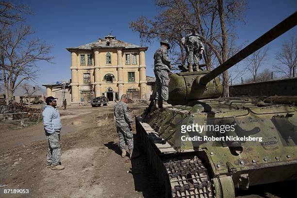 Army soldiers examine a broken down Soviet tank in front of a Soviet built house in the district center of Moqur, Afghanistan March 25, 2008. The...