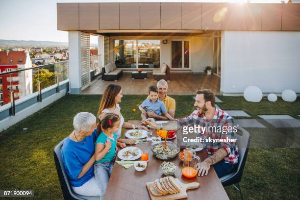 feliz familia almorzando en el balcón frente a su ático. - penthouse girl fotografías e imágenes de stock