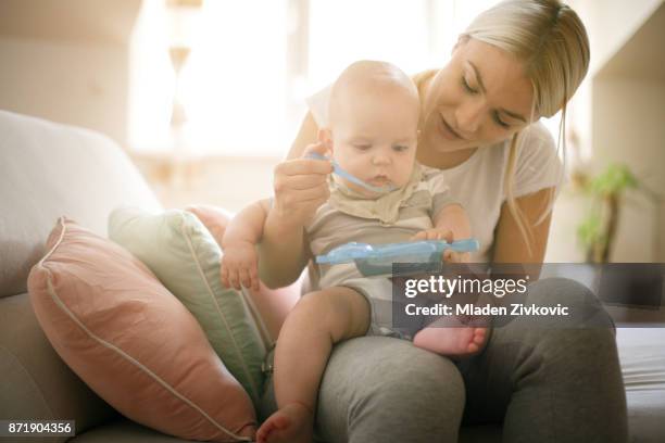 mamma matar sin lilla baby pojke hemma. närbild. - babymat bildbanksfoton och bilder