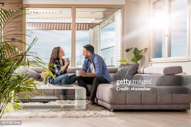 young happy couple talking to each other during coffee time at home. - women of penthouse stock pictures, royalty-free photos & images