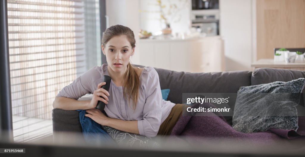 Young woman watching TV alone