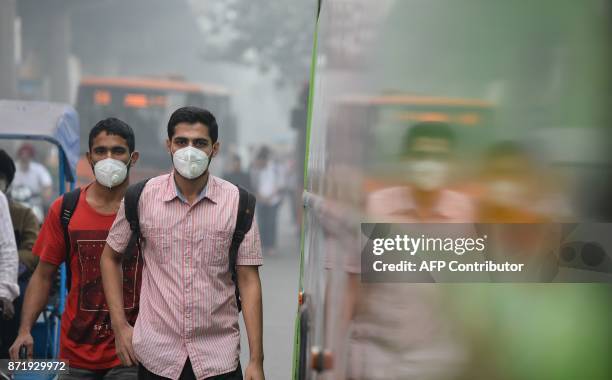 Indian commuters wear masks as they walk along a road amid heavy smog in New Delhi on November 9, 2017. Rickshaw driver Sanjay can only afford a...