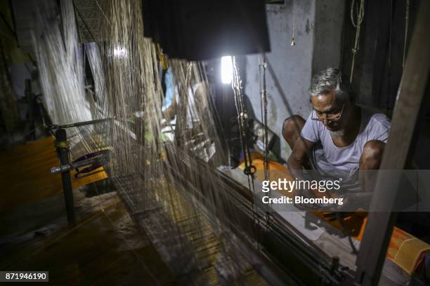 Weaver looks at a design template while sitting at a handloom making a silk saree in a workshop at night in Varanasi, Uttar Pradesh, India, on...