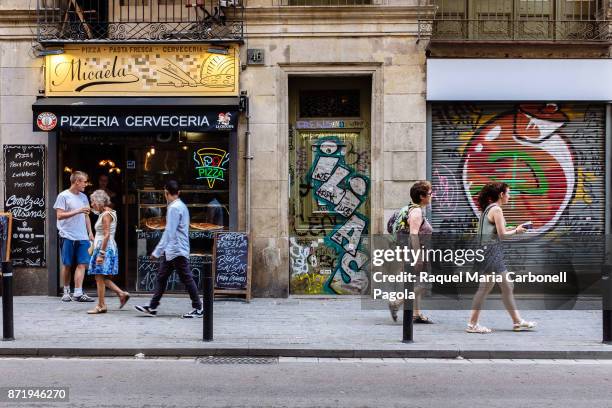 Tourists coming out of an italian pizza restaurant next to graffiti painted doorways.