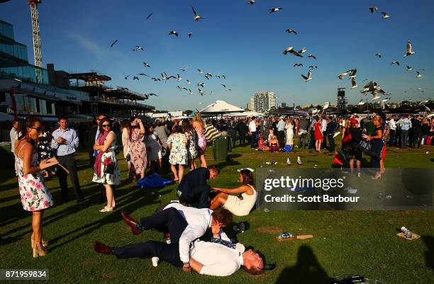 Racegoers fall to the ground as they make their way from the course following 2017 Oaks Day at Flemington Racecourse on November 9, 2017 in...