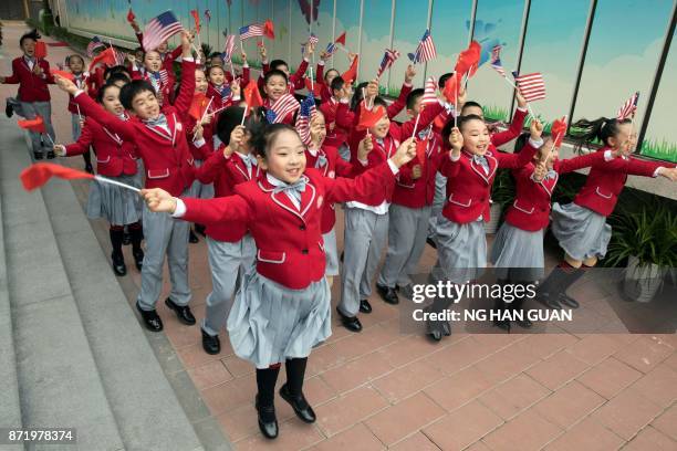 Students wave US and Chinese flags as they send off US First Lady Melania Trump and China's First Lady Peng Liyuan after their visit to the Banchang...