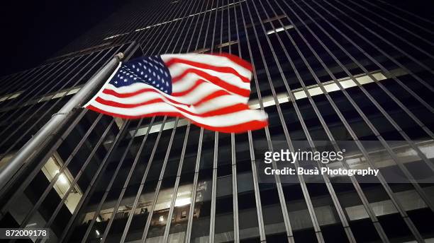 american flag along 34th street in midtown manhattan, at night. new york city, usa - flagpole sitting stockfoto's en -beelden