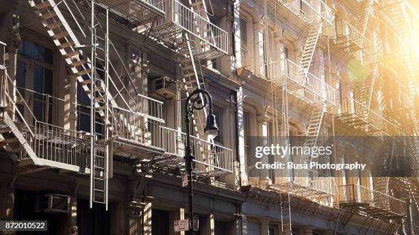 facades of typical cast iron buildings with fire escapes along greene street in the soho cast iron historic district, manhattan, new york city - soho new york stock pictures, royalty-free photos & images