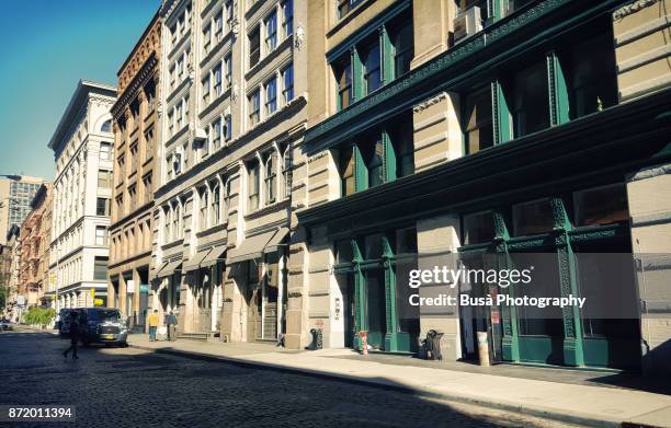 facades of typical cast iron buildings with fire escapes along greene street in the soho cast iron historic district, manhattan, new york city - soho new york stockfoto's en -beelden