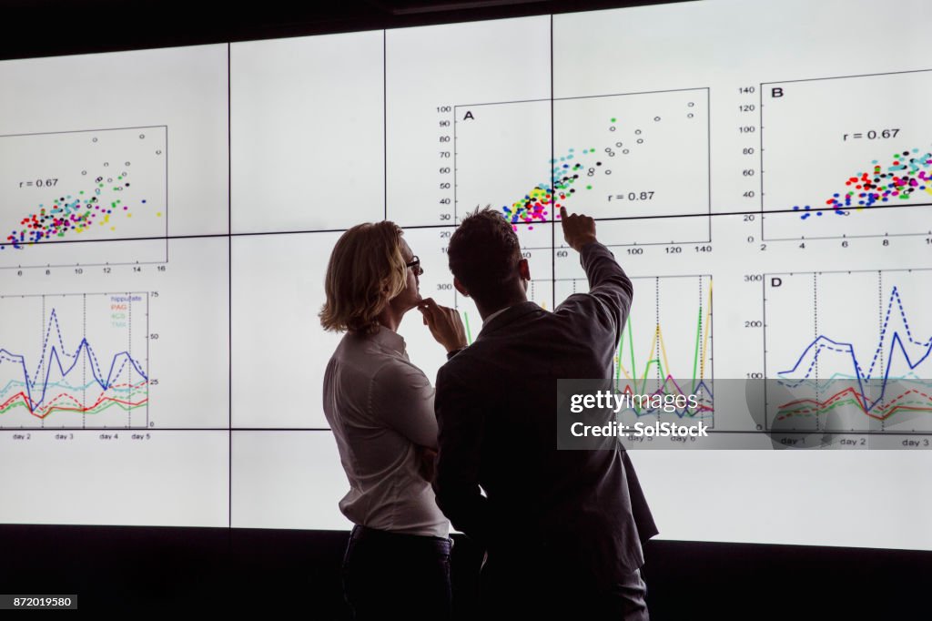 Men Viewing a Large Screen of Information