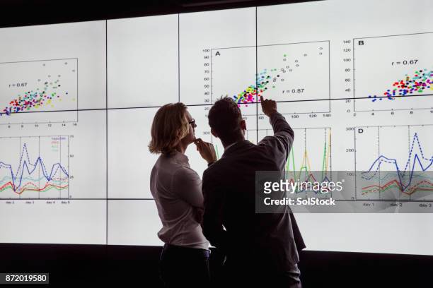 men viewing a large screen of information - innovation imagens e fotografias de stock
