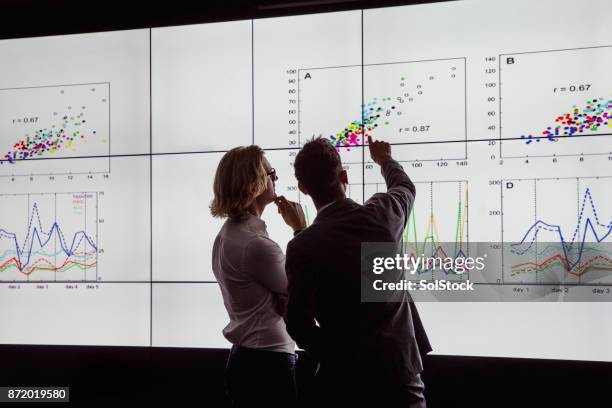 men viewing a large screen of information - examinar imagens e fotografias de stock