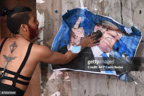 Member of an LGBT group defaces a portrait of US President Donald Trump during a rally inside the state university campus in Los Banos town, Laguna...