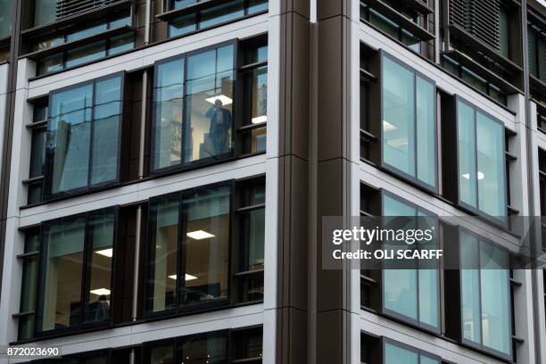 An office worker looks out from the window of the offices of a financial institution in St Helier, on the British island of Jersey, on November 9,...