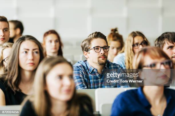 young students concentrating on professor during lecture - adulto foto e immagini stock