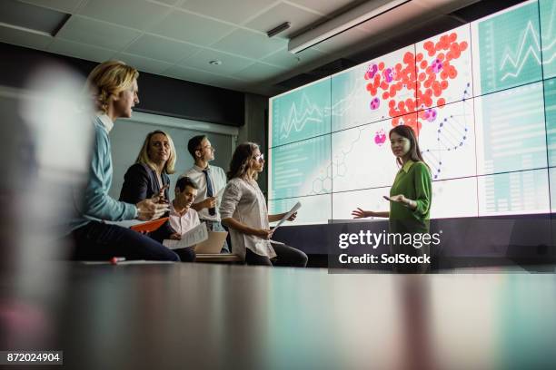 meeting in front of a large display screen - scientist imagens e fotografias de stock