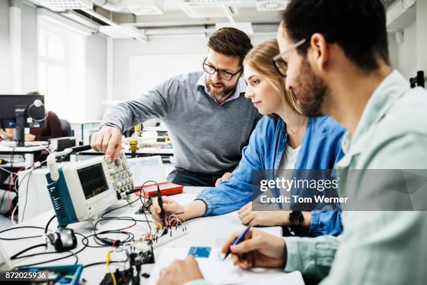 university tutor showing students how to use electronic equipment - differential focus education stock pictures, royalty-free photos & images