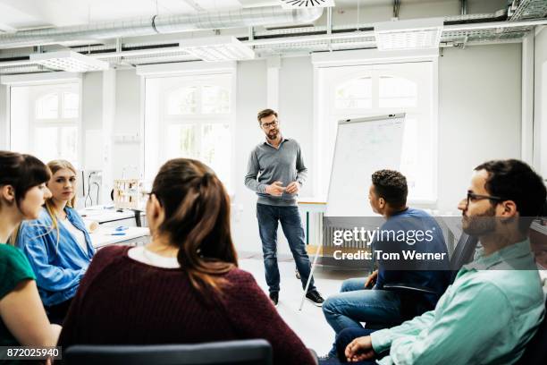 tutor listening to students during university seminar - volwassen stockfoto's en -beelden