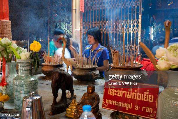 Woman in prayer holding incense sticks, Temple complex in the Trang Buddhist Temple. Trang, also called Mueang Thap Thiang, is one of the southern...