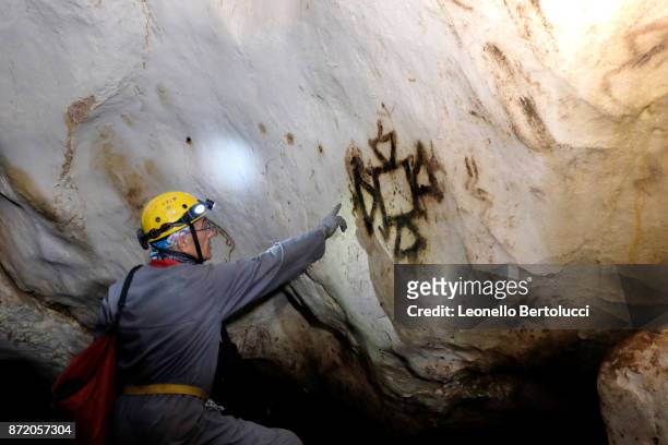 Scientific director of the "Gruppo Speleologico Salentino", Nini Ciccarese studies a pictogram in the “Grotta dei Cervi” on July 31, 2017 in Salento,...