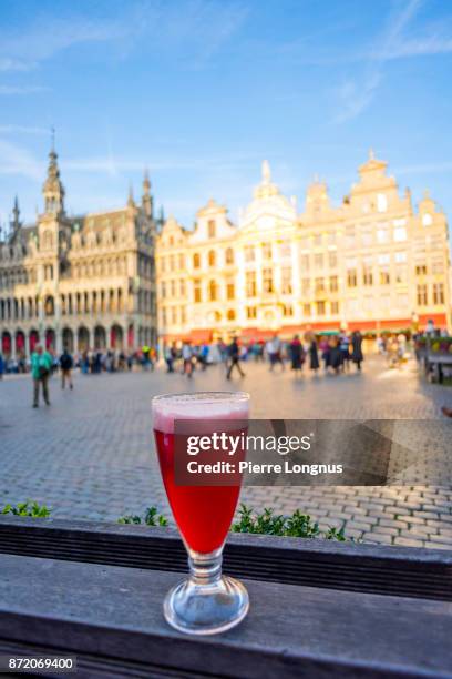 glass of cherry flavored traditional belgian beer on an outdoor counter on the grand place, unesco world heritage site, brussels, belgium - belgium beer stock pictures, royalty-free photos & images