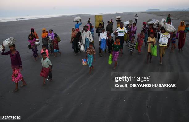 Rohingya Muslim refugees who entered Bangladesh by boat walk towards refugee camps after landing at the Saplapur beach in the Teknaf district of...