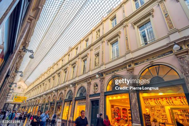 shoppers and tourists strolling under the glass-roofed of galeries royales saint-hubert, one of several arcade galleries in brussels, belgium - st hubert galleries stock-fotos und bilder