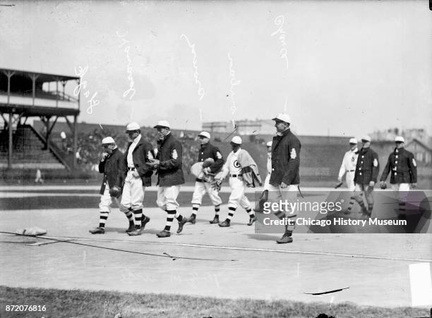 Chicago Cubs baseball players walk off the field, near second base, during a game against the Cincinnati Reds at West Side Grounds, Chicago,...