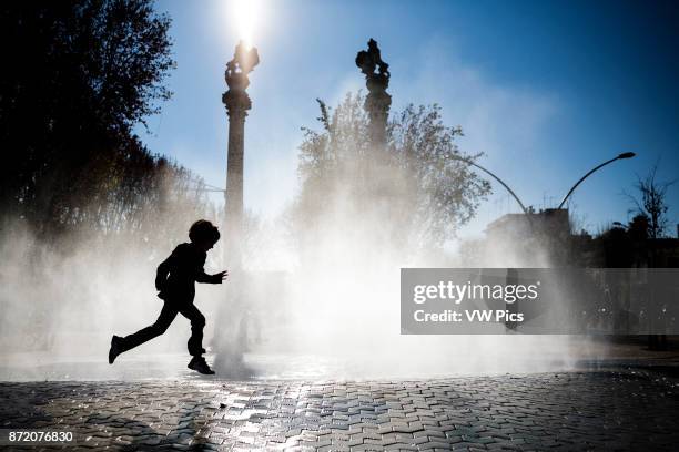 Little girl playing in front of a fountain, Alameda de Hercules square, Seville, Spain.