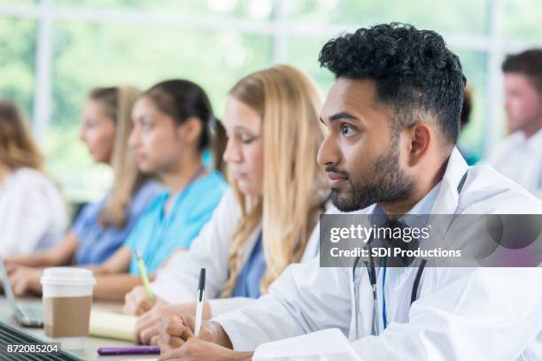 attentive medical student takes notes during class - american college of physicians stock pictures, royalty-free photos & images