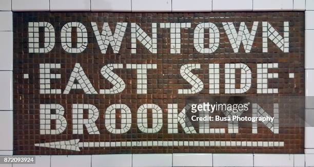 new york city, ny, usa - october 10, 2017: colorful ceramic plaques and tile mosaics in the new york city subway. mosaic directing passengers in direction downtown - east side - brooklyn - brooklyn new york stockfoto's en -beelden