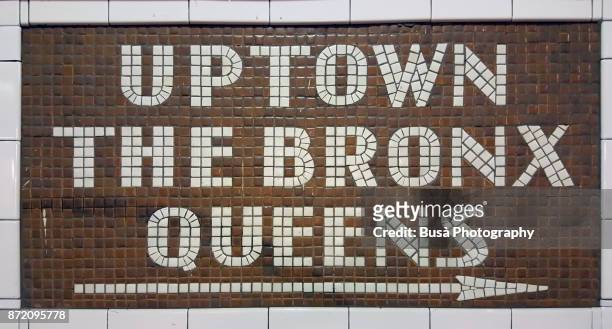 new york city, ny, usa - october 10, 2017: colorful ceramic plaques and tile mosaics in the new york city subway. mosaic directing passengers in direction: uptown - the bronx - queens - bronx stock-fotos und bilder