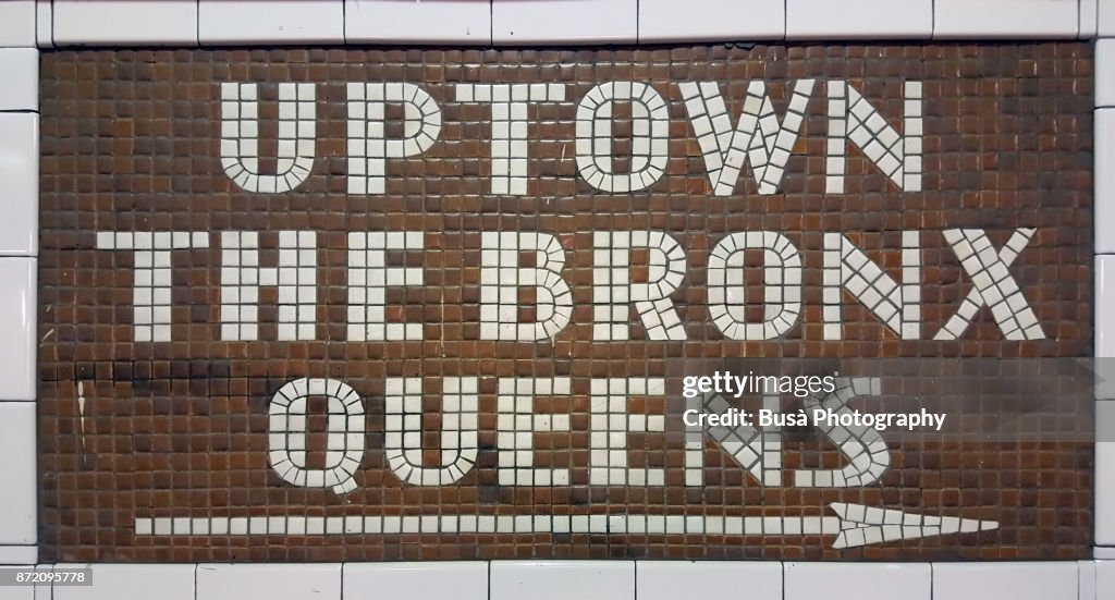 New York City, NY, USA - October 10, 2017: Colorful ceramic plaques and tile mosaics in the New York City subway. Mosaic directing passengers in direction: Uptown - The Bronx - Queens