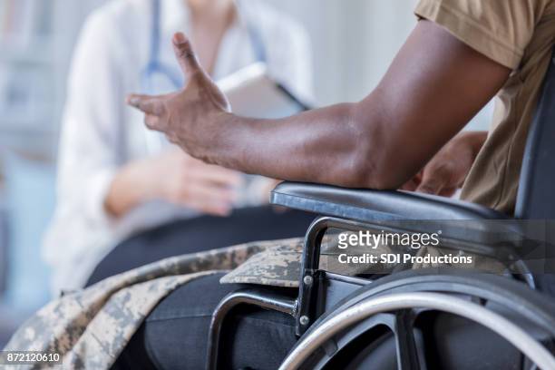 unrecognizable wounded warrior discusses symptoms with doctor - african injured stock pictures, royalty-free photos & images