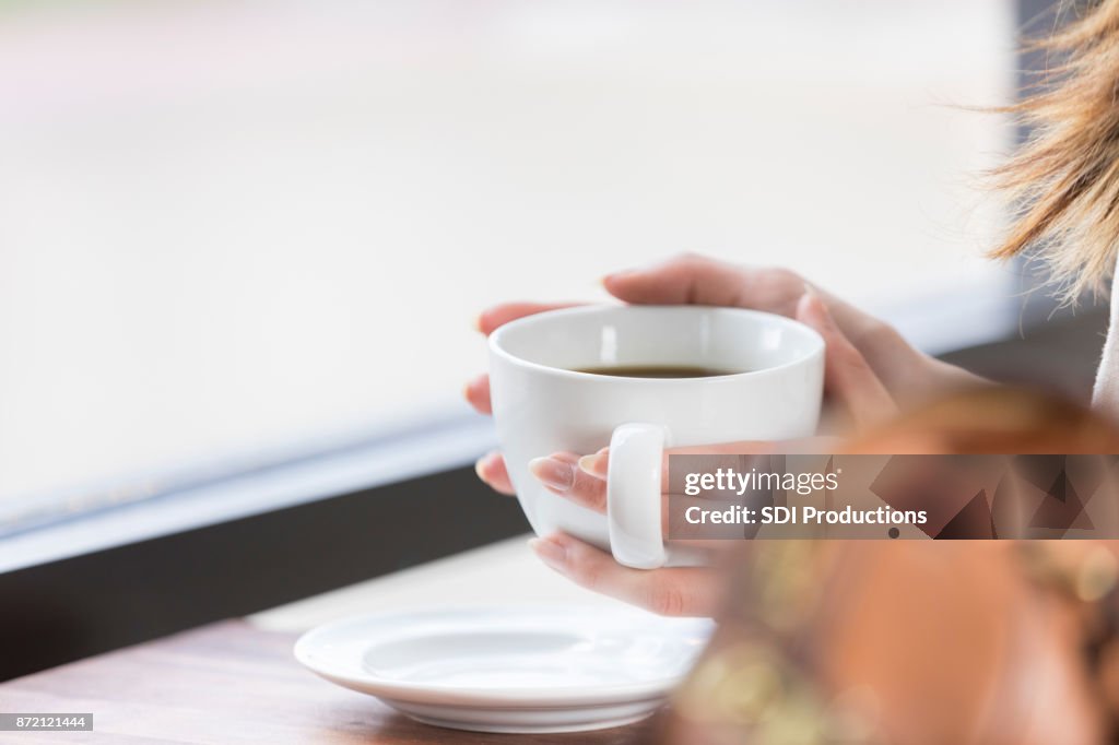 Coffee cup being lifted by coffee shop customer