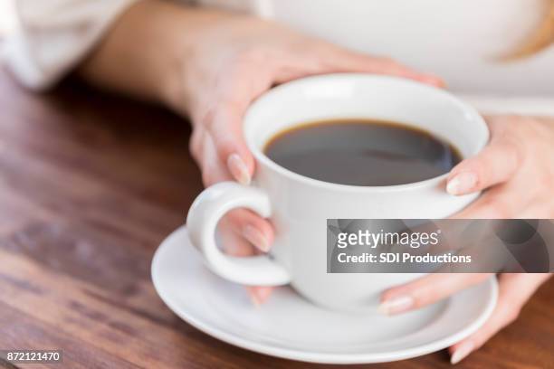 primer plano de dos manos alrededor de la taza de café en mesa - célula cultivada fotografías e imágenes de stock