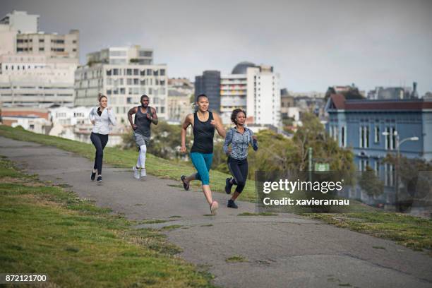 four multi-ethnic people running on a park in san francisco, california, usa - san francisco marathon stock pictures, royalty-free photos & images