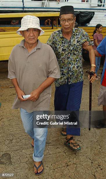 Lijo Castro , a freed hostage who was held by Abu Sayyaf guerrillas for seven months, walks to a ferry with a Muslim Imam June 29, 2002 on the...