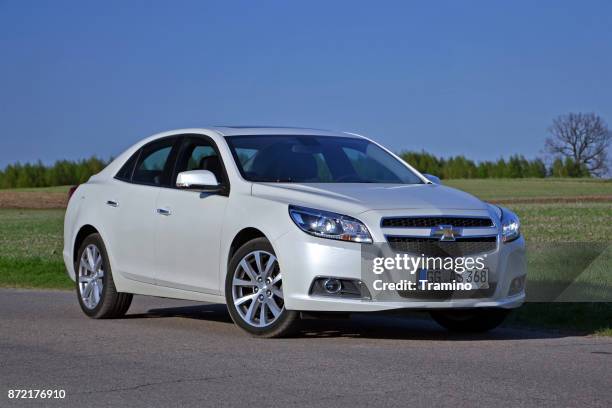 chevrolet malibu auf der straße - limousine familienfahrzeug stock-fotos und bilder