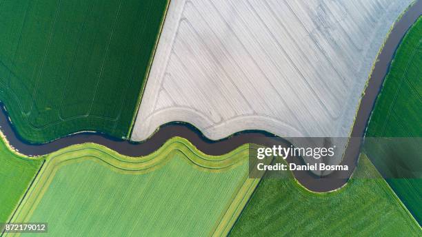 cultivated land with natural stream seen from above - river aerial stock-fotos und bilder