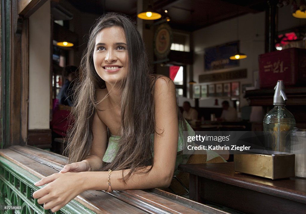 Young woman leaning on window, smiling