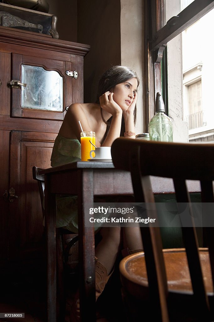 Young woman sitting in café, looking away