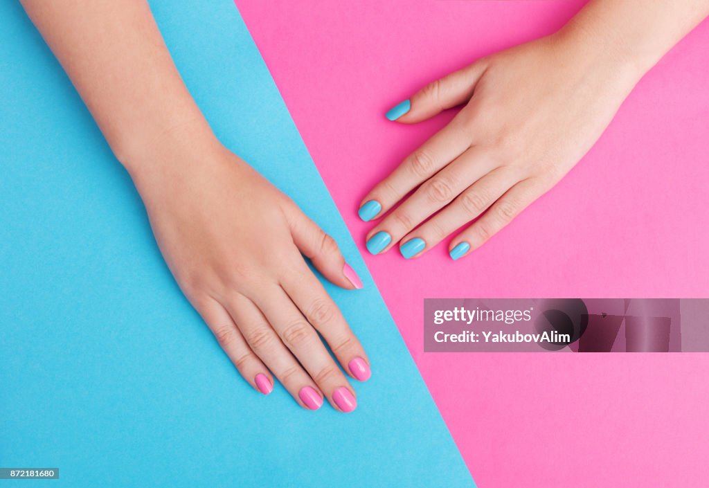 Closeup de mãos de uma jovem mulher com manicure unhas contra fundo rosa
