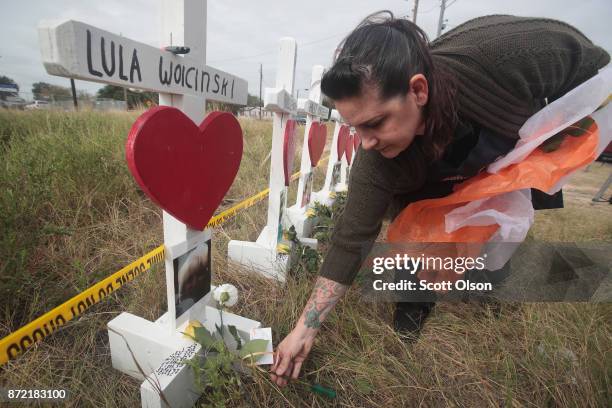 Joyce Mires leaves flowers at a memorial where 26 crosses were placed to honor the 26 victims killed at the First Baptist Church of Sutherland...