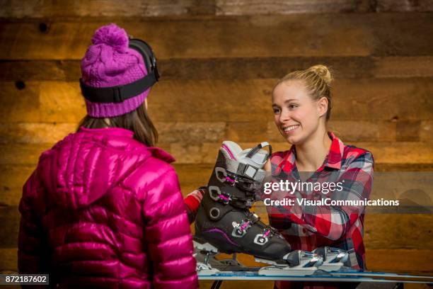 vrouwelijke sales assistant afstemmen op ski's voor de klant. - skischoen stockfoto's en -beelden