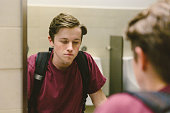 Depressed teen looks at himself in bathroom mirror