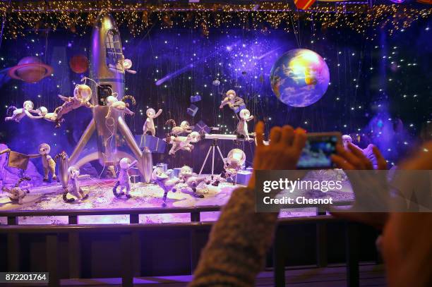 Visitor takes a picture of the Christmas window display of the "Le Printemps Haussmann" department store after the inauguration of the store's...