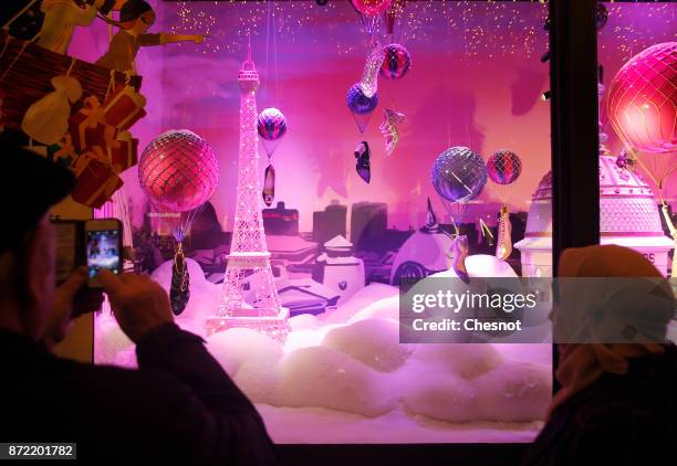 Visitor takes a picture of the Christmas window display of the "Le Printemps Haussmann" department store after the inauguration of the store's...