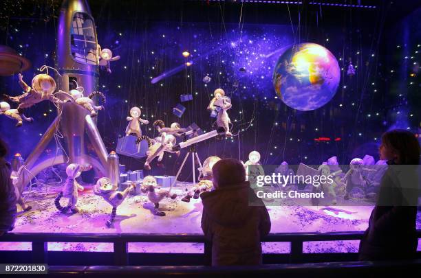 Children look at the Christmas window display of the "Le Printemps Haussmann" department store after the inauguration of the store's illuminations...